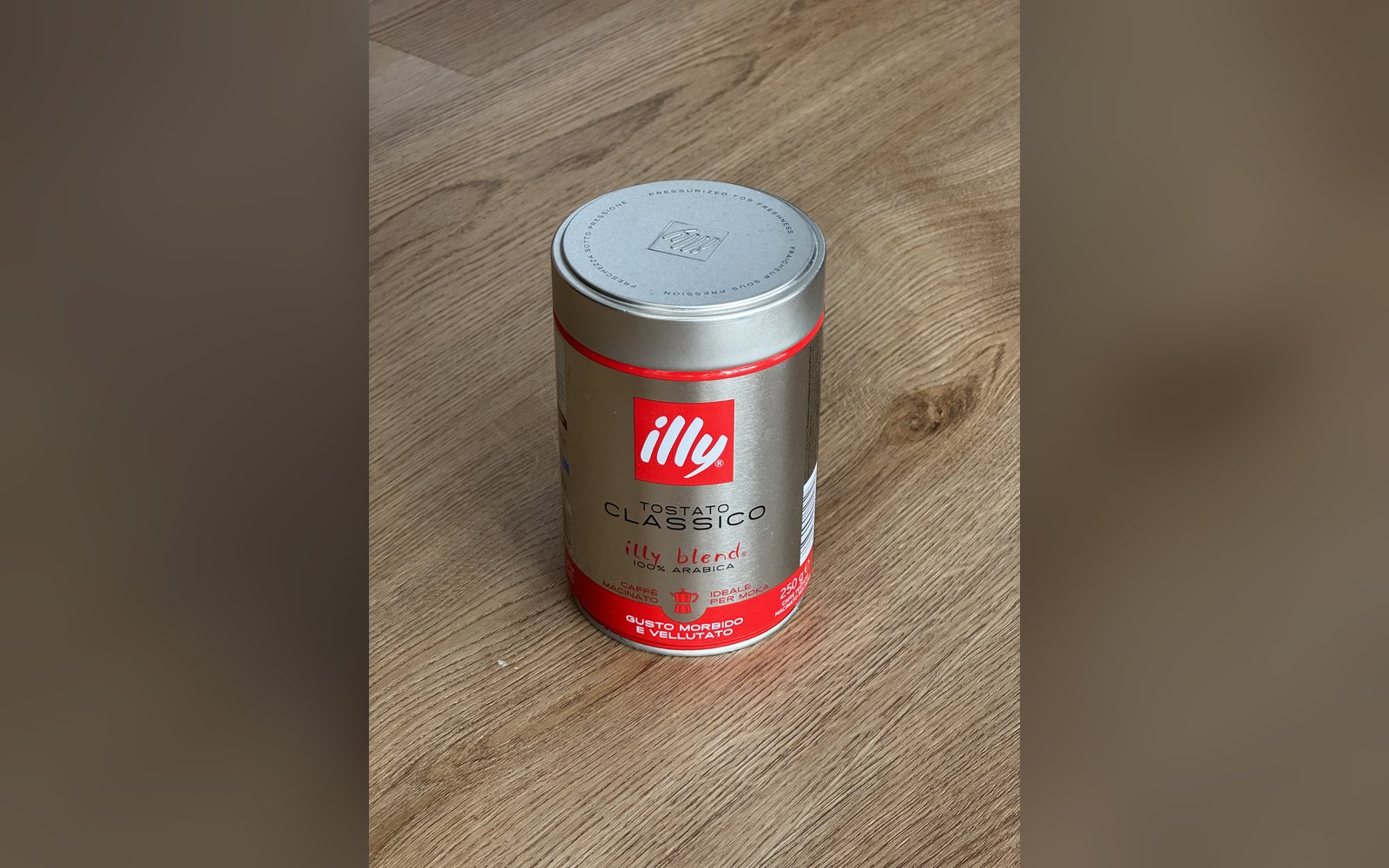 Latta di caffè fotografata col telefono sul pavimento
